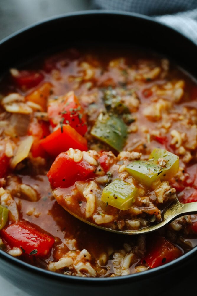 Stuffed pepper soup is delicious, hearty, and full of flavor! Filled with so many different ingredients, it's insanely good and will definitely fill your belly! Zoomed in picture of a spoon scooping up some stuffed pepper soup.