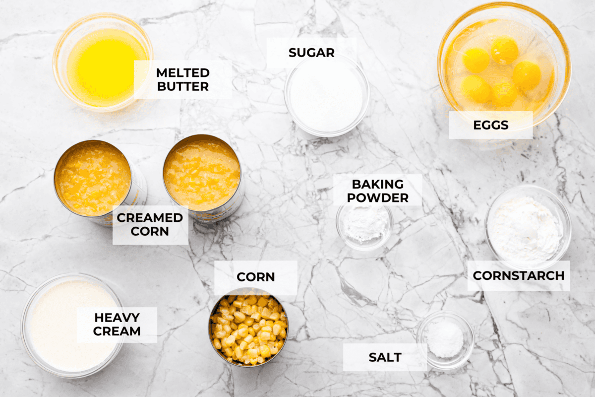 Corn pudding is creamy, slightly sweet, with a hint of savory! It's packed with cream, butter, sweet and juicy corn kernels, all baked to perfection. It will be an awesome addition to your Thanksgiving spread, or make it for any weeknight. Overhead shot of labeled ingredients.