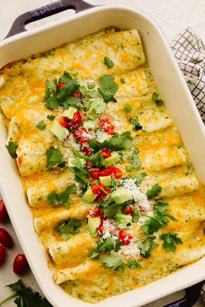 My easy breakfast enchiladas are packed with sausage, fluffy eggs, and zesty salsa, then smothered in a rich, creamy sauce that puts every other breakfast to shame. You can even make them ahead! A casserole dish filled with breakfast enchiladas.