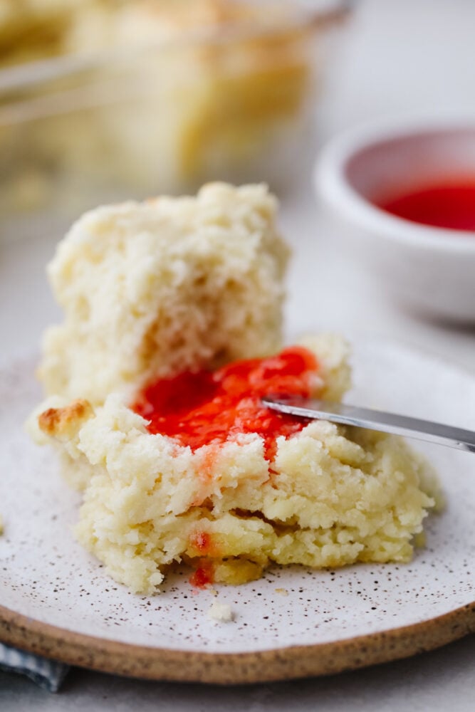 These swim butter biscuits are soft and fluffy on the inside with a crisp outside edge. They are SOO GOOD and will go with just about anything! Swim butter biscuit with some strawberry jam being spread on one with a knife.