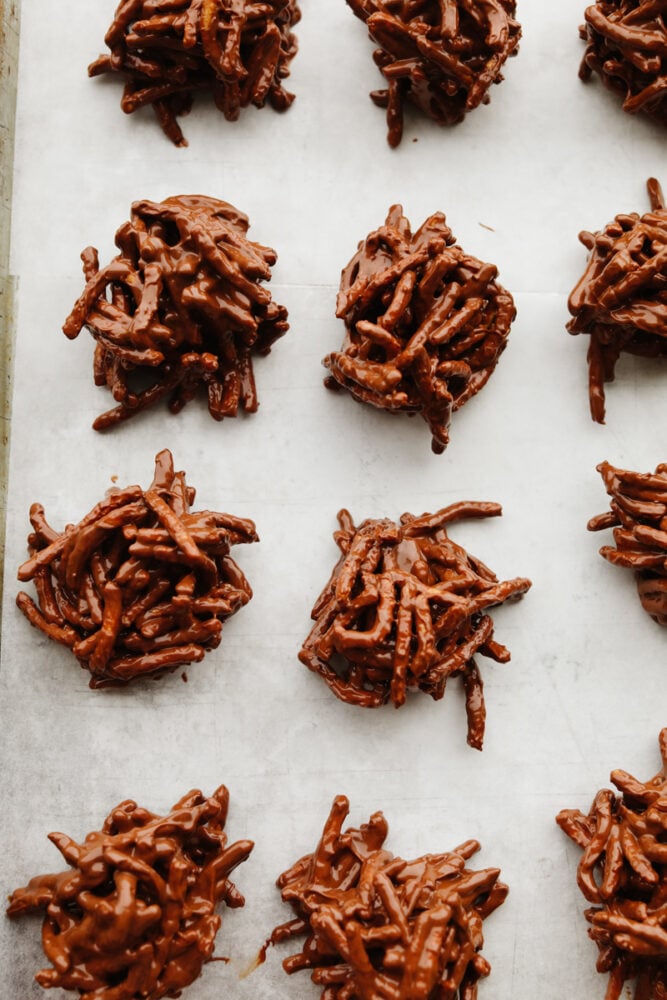 Haystack cookies are perfect for the holidays! They are festive, have the perfect crunch, and are so good that you won't be able to stop at just one! Chocolate haystack cookies on parchment paper on a baking sheet.