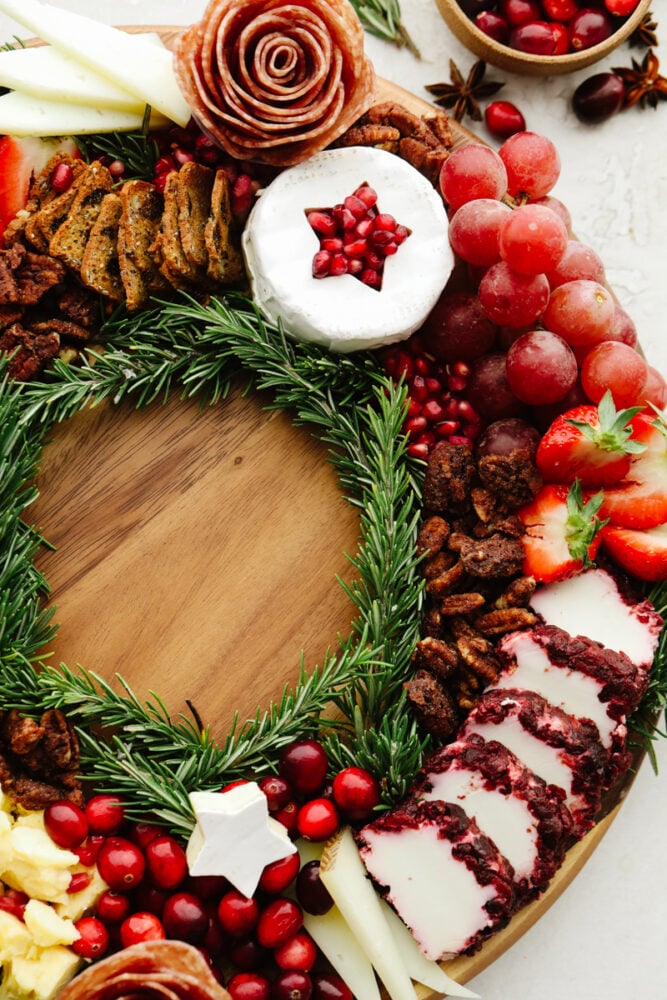 This Christmas wreath charcuterie board is the perfect festive touch to any holiday party! It's stunning and delicious! Plus, it's super easy to make and all of your guests will be so impressed! A close up of the side of the charcuterie board with nuts, cheeses and cranberries.