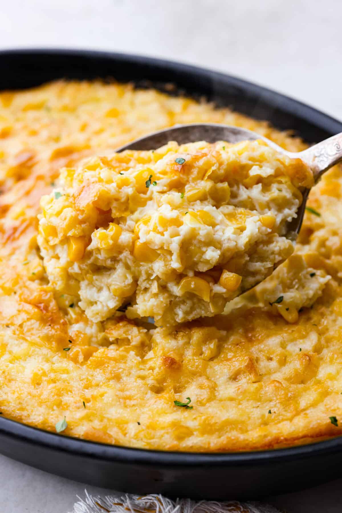 Corn pudding is creamy, slightly sweet, with a hint of savory! It's packed with cream, butter, sweet and juicy corn kernels, all baked to perfection. It will be an awesome addition to your Thanksgiving spread, or make it for any weeknight. Close up shot of corn pudding in a serving spoon.