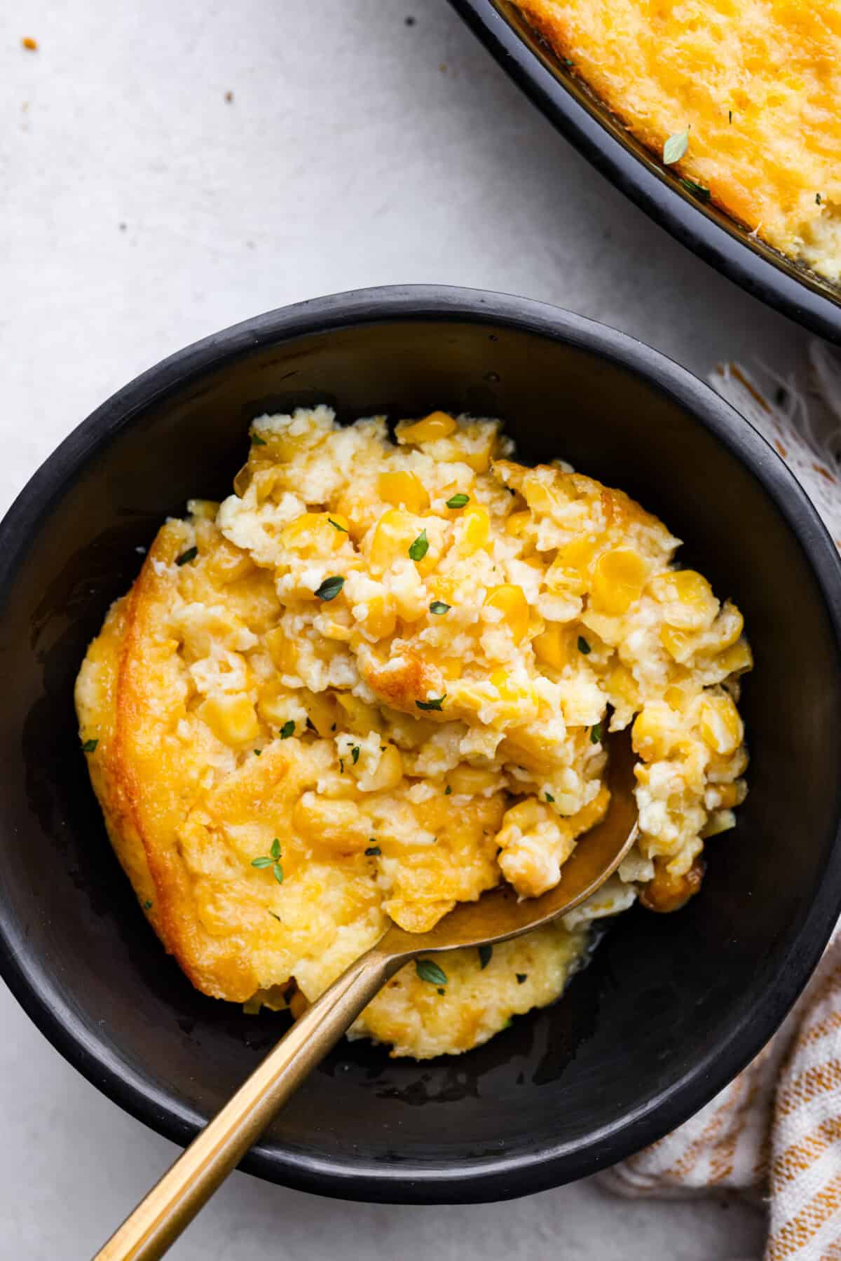 Corn pudding is creamy, slightly sweet, with a hint of savory! It's packed with cream, butter, sweet and juicy corn kernels, all baked to perfection. It will be an awesome addition to your Thanksgiving spread, or make it for any weeknight. Overhead shot of a bowl of corn pudding.