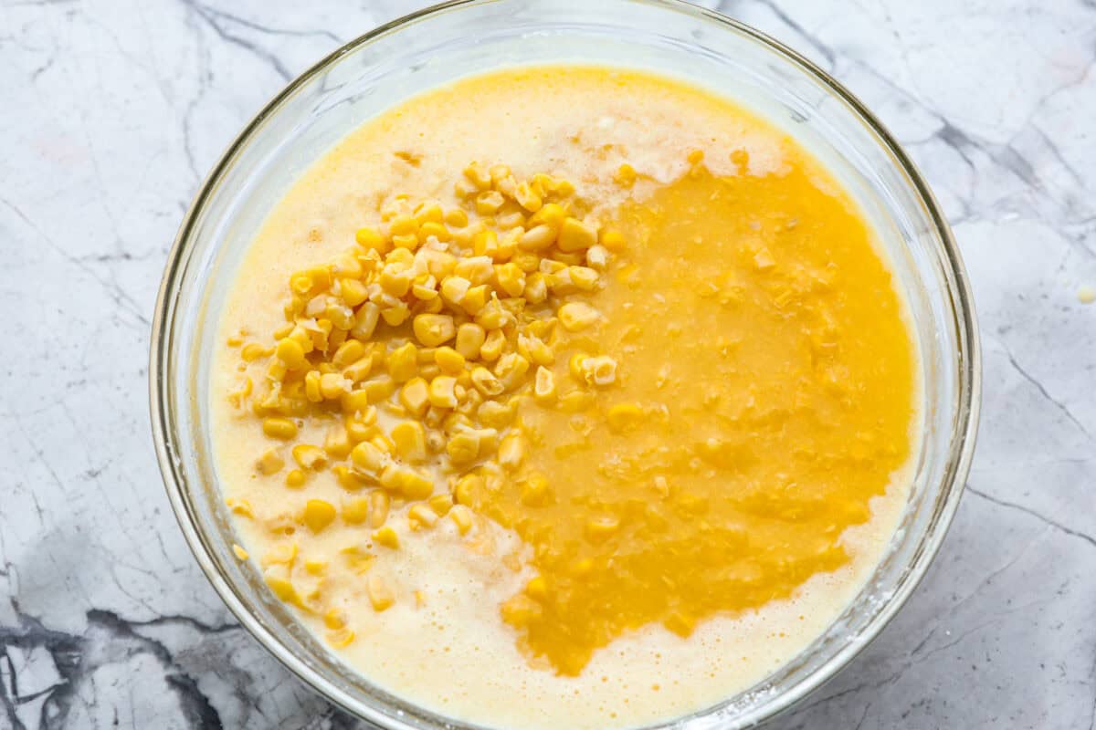Corn pudding is creamy, slightly sweet, with a hint of savory! It's packed with cream, butter, sweet and juicy corn kernels, all baked to perfection. It will be an awesome addition to your Thanksgiving spread, or make it for any weeknight. Overhead shot of egg and cornstarch mixture with corn, creamed corn, butter, and heavy cream in a glass bowl.
