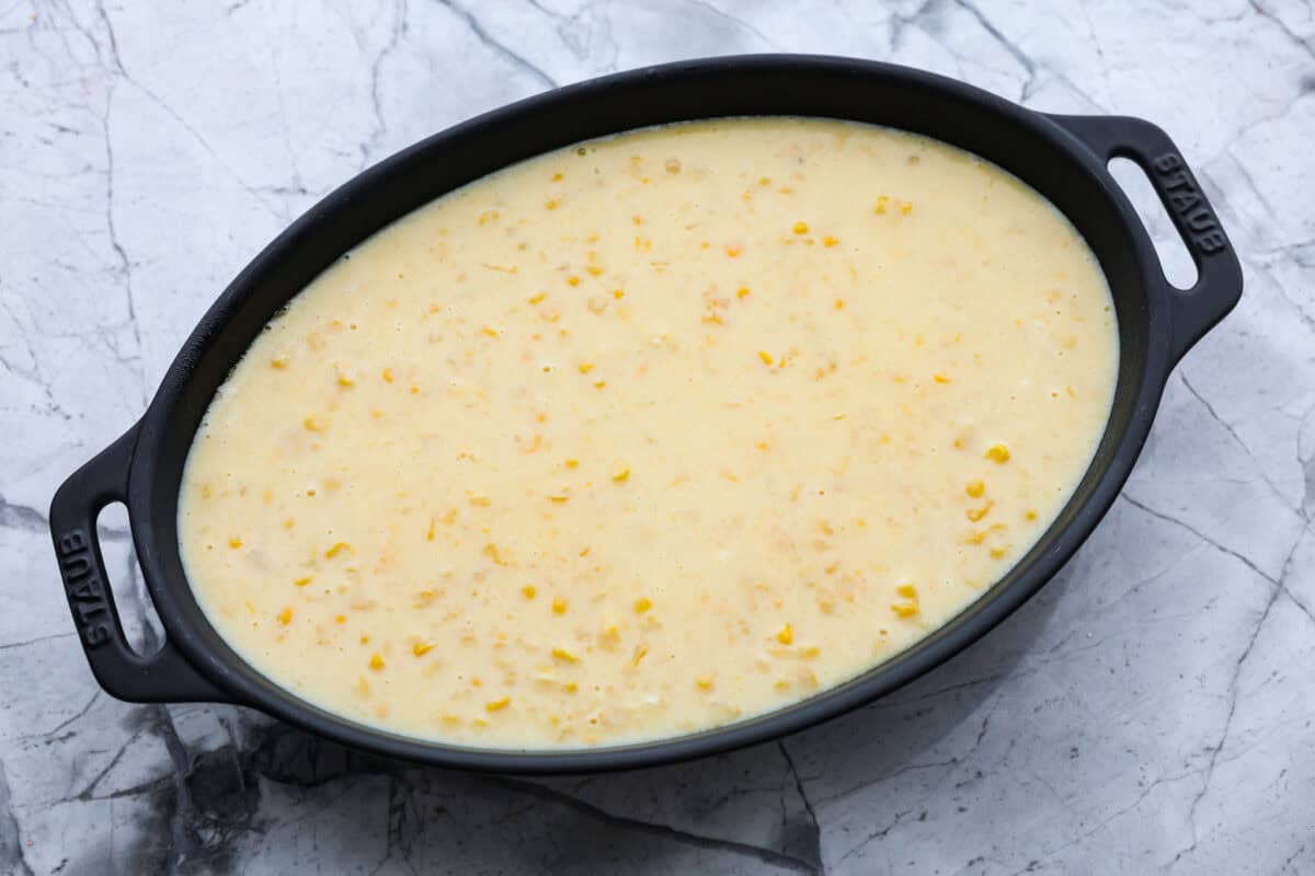 Corn pudding is creamy, slightly sweet, with a hint of savory! It's packed with cream, butter, sweet and juicy corn kernels, all baked to perfection. It will be an awesome addition to your Thanksgiving spread, or make it for any weeknight. Overhead shot of corn pudding ingredients in a baking dish ready to go in the oven.