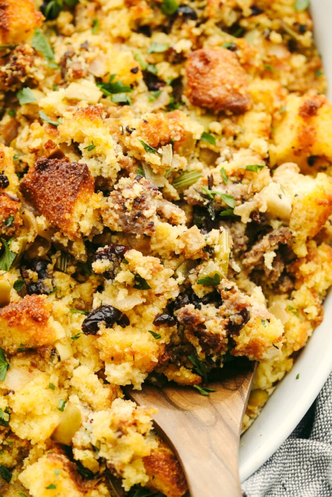 Cornbread stuffing is a delicious hearty dish that your family will go crazy over this Thanksgiving! It's loaded with fresh herbs, fruits, and veggies for the perfect sweet and savory side. Closeup of cornbread stuffing.