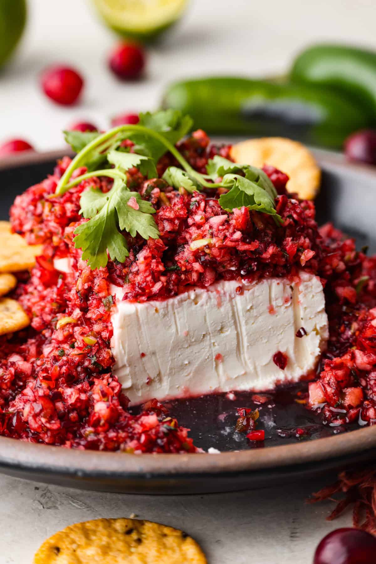 Cranberry salsaย is a fresh cranberry mixture of sweet and savory that is laid over cream cheese. It makes for the BEST holiday appetizer! You can also serve it in place of cranberry sauce with your Thanksgiving dinner. Close up shot of cranberry salsa over cream cheese on a serving platter.