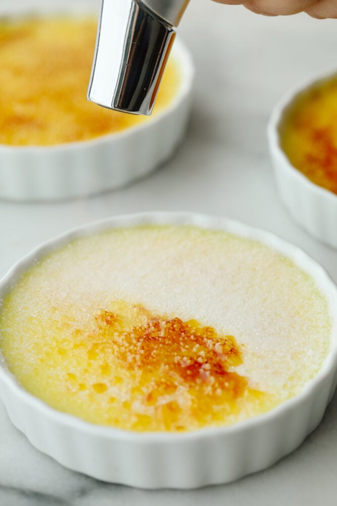 This creme brรปlรฉeย is a simple but elegant dessert that will impress all of your guests! You just can't beat a creamy custard topped with caramelized sugar and delicious fresh fruit! A picture showing how to torch the sugar.