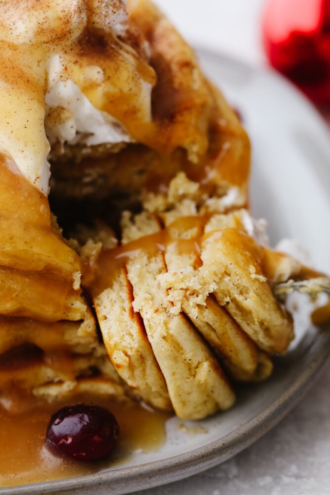 These eggnog pancakes are a MUST TRY this holiday season! They are soft and sweet and will melt right in your mouth. The hint of eggnog will have everyone coming back for more! Eggnog pancakes being sliced with a fork.