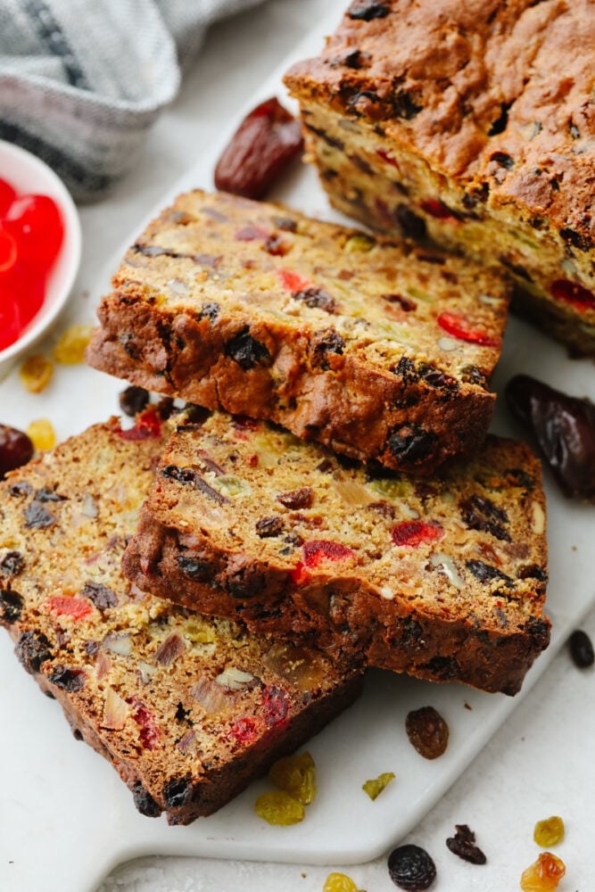 Fruit cake is a classic holiday dessert that you're going to love! With this recipe, you'll get a moist, flavorful treat every time! Fruit cake cut into slices on a white serving dish.