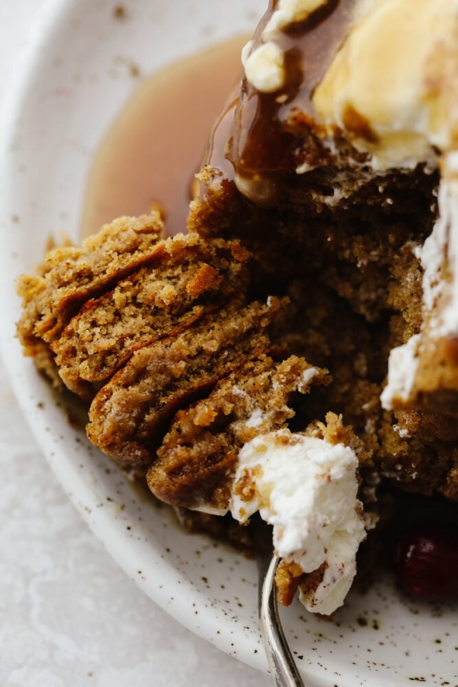 Add holiday spice to your breakfast with these amazing gingerbread pancakes! Soft, fluffy, and drizzled in a homemade caramel sauce, this is a treat you won't want to pass up! Closeup of a stack of pancakes cut through with a fork.