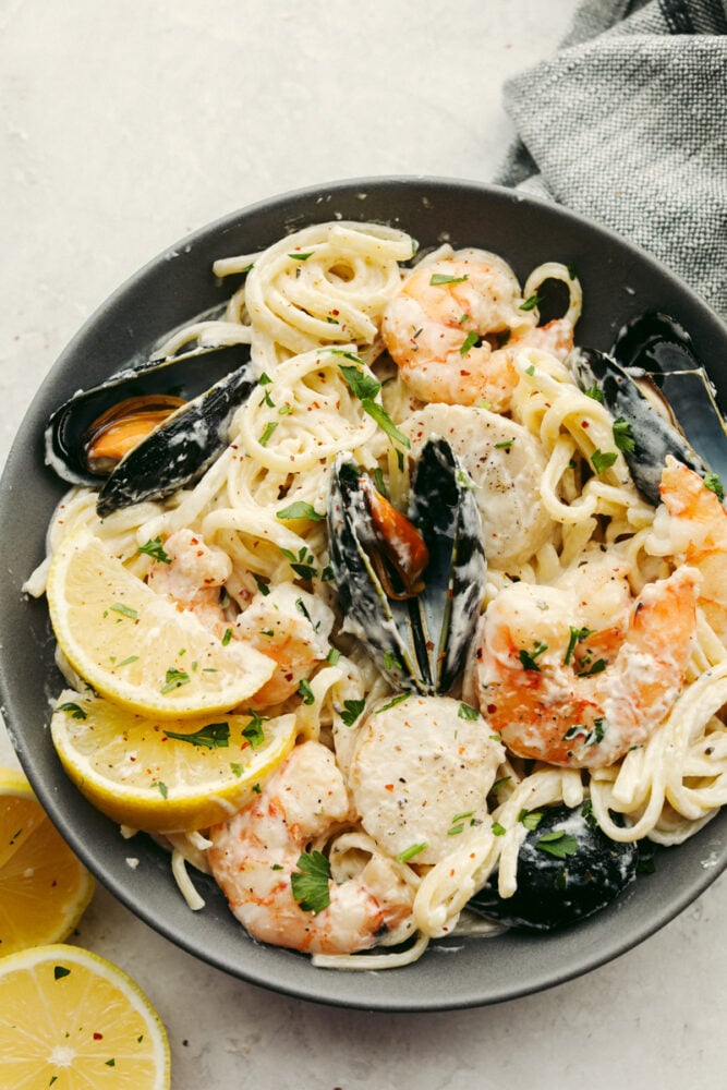 My seafood pasta has a silky lemon garlic cream sauce that is to die for! It's loaded with tender shrimp, scallops, and mussels. Itโs the perfect date night dish! A pan filled with pasta and shellfish, ready to eat.