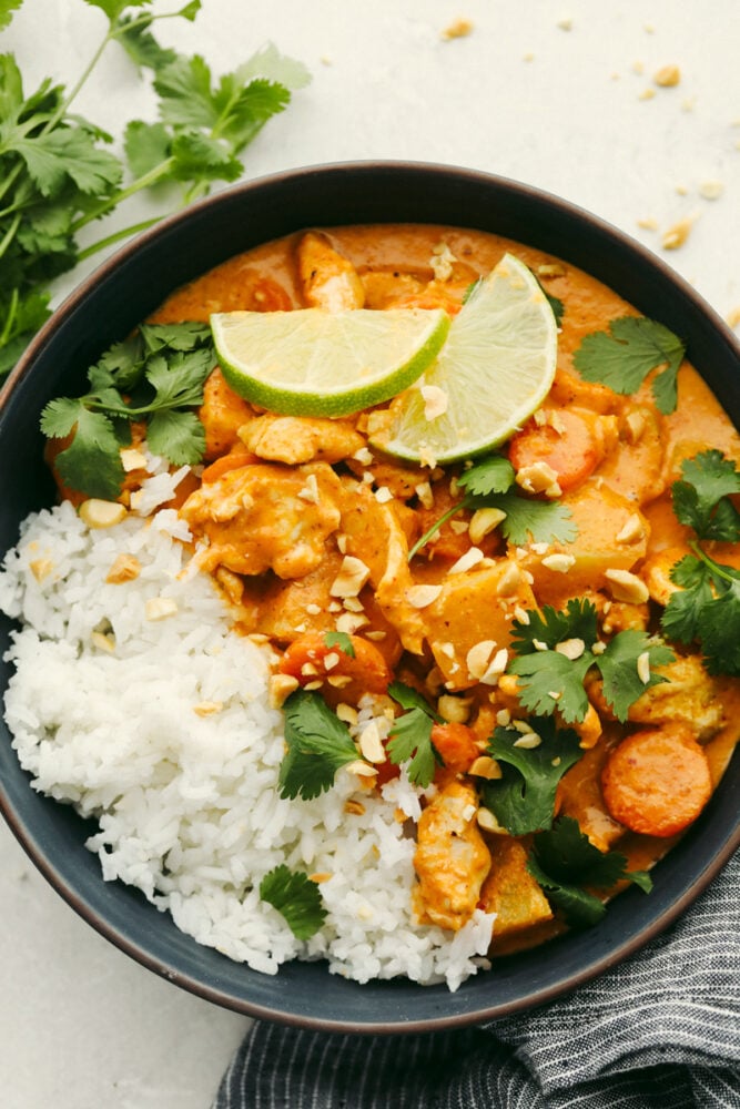 This massaman curry is insanely delicious!! Tender and juicy chicken mixed with a creamy blend of flavors gives it the best taste that ALL of your guests will love!! Massaman curry in a bowl with garnish and rice.