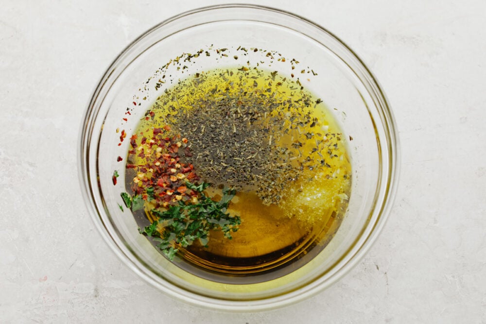 This olive oil bread dip is the absolute perfect appetizer! It has just the right blend of spices that taste SOO GOOD! It will definitely get a "WOW!" from all of your guests! a bowl with olive oil and spices being mixed into it.