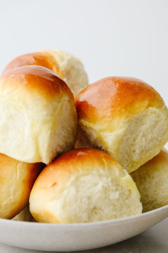 These 1-hour dinner rolls are the perfect solution for making fresh bread in a pinch! This easy and delicious roll recipe will become your new favorite, just in time for the holidays! Rolls stacked in a white bowl.