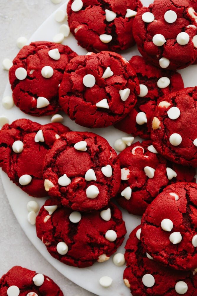 Delicious and chewy red velvet cookies with white chocolate chips. Rich, sweet, with a hint of tang, this is the dessert you'll be needing for all of your holiday parties! Red velvet cookies on a white plate.