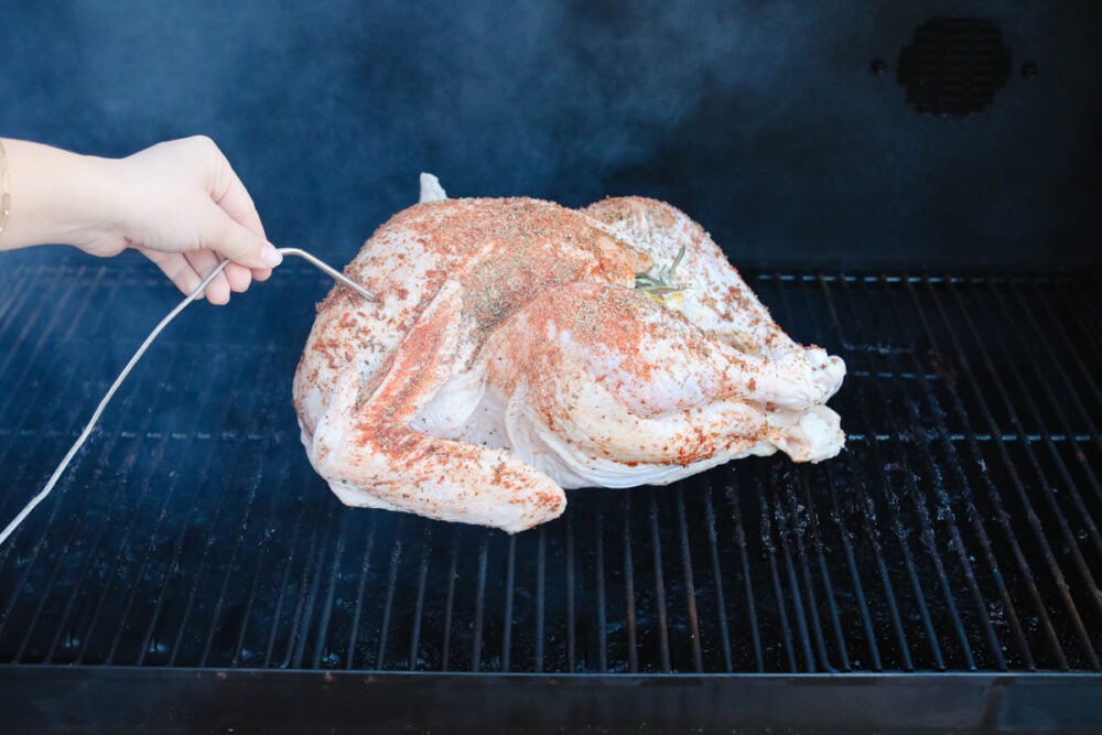 Just in time for Thanksgiving, this perfect smoked turkey is juicy and tender with a subtle smoky flavor. A simple brine and fresh herbs make each bite burst with flavor! Checking the internal temperature of while it smokes.