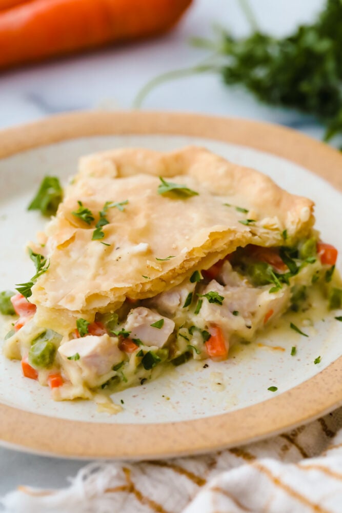 This turkey pot pie is a hearty and classic dinner! It has a flakey crust and a creamy, vegetable and turkey filling that your entire family will go crazy over! A slice of turkey pot pie on a plate.