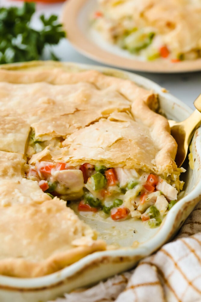 This turkey pot pie is a hearty and classic dinner! It has a flakey crust and a creamy, vegetable and turkey filling that your entire family will go crazy over! A turkey pot pie with a slice cut out of it.