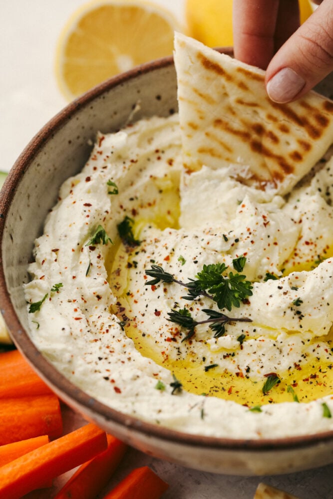 It doesn't get much better than whipped feta dip!! Perfectly creamy and garnished with herbs and spices, this dip will be the talk of the party! A close up of whipped feta dip.