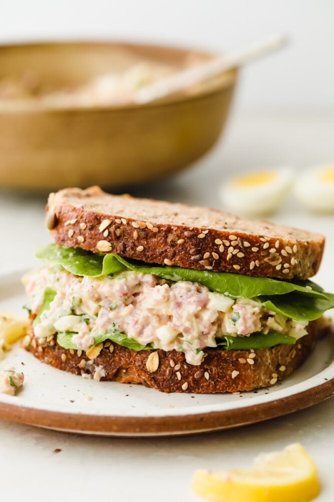 This amazing ham salad is filled with so much flavor! Super simple and easy to make, use some leftover ham and you can whip this up for lunch in under 10 minutes!ย A ham salad sandwich on a plate.