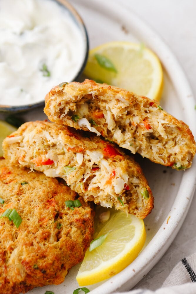 Air fryer crab cakes are an amazing appetizer that comes together in a snap! Each bite is tender, savory, and packed with all the crab flavor you crave! Closeup of a crab cake split in 2 pieces.