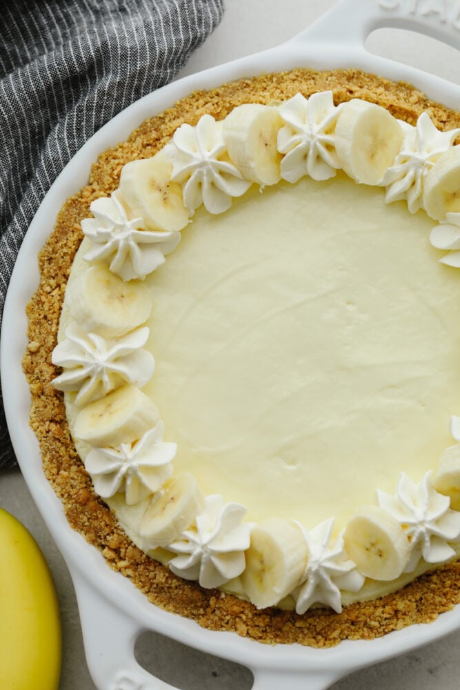 You don't even need an oven to make this banana cream cheesecake! This has a crust and a perfectly creamy filling. Top it with some whipped cream and fresh bananas and you won't be able to stop at one slice! Top view of a banana cream cheesecake.