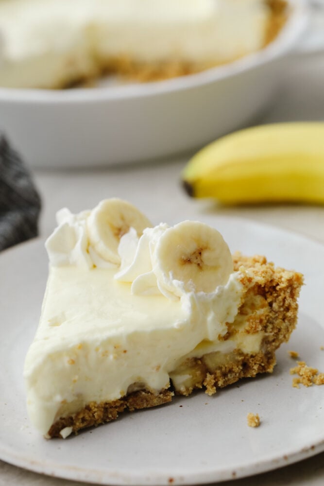 You don't even need an oven to make this banana cream cheesecake! This has a crust and a perfectly creamy filling. Top it with some whipped cream and fresh bananas and you won't be able to stop at one slice! A slice of bo-bake cheesecake on a plate.