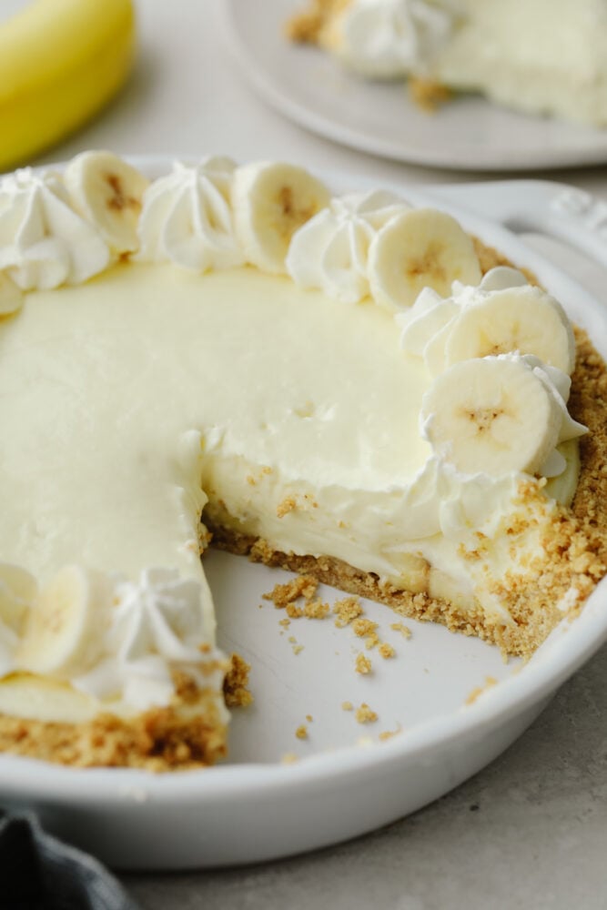 You don't even need an oven to make this banana cream cheesecake! This has a crust and a perfectly creamy filling. Top it with some whipped cream and fresh bananas and you won't be able to stop at one slice! Banana cream cheesecake in a pie pan with a slice taken out.
