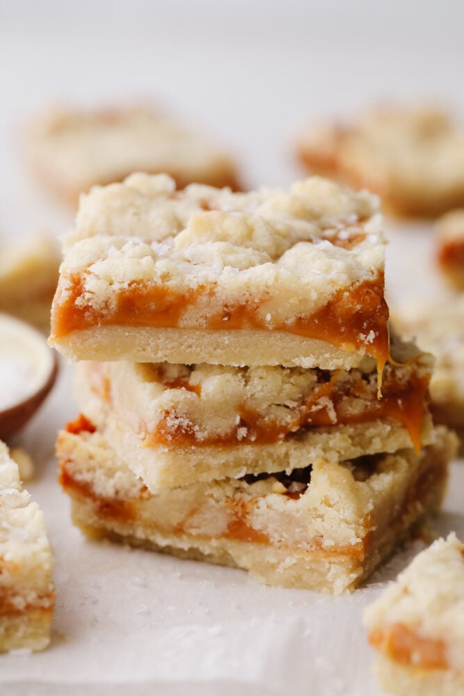 Salted caramel butter bars are the perfect easy-to-make dessert. With a buttery and crumbly shortbread crust that is topped with a smooth layer of caramel, there will be a little bit of sweet and savory in each bite! A stack of salted caramel butter bars.
