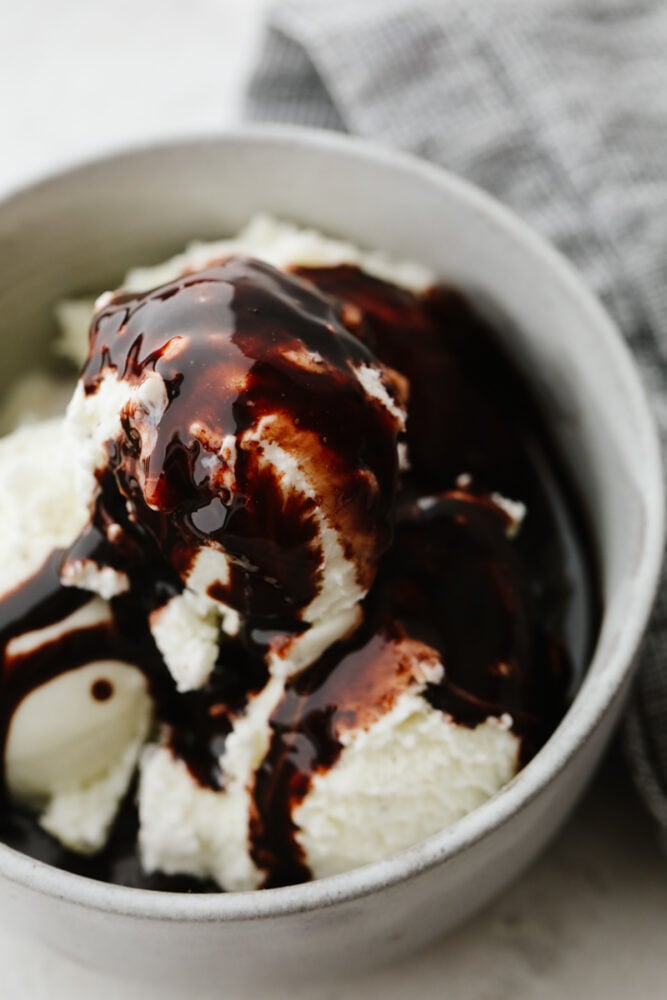This homemade chocolate sauce has the perfect chocolate flavor and the smooth texture is to die for. It goes on just about anything and is so simple to make! Ice cream in a bowl with chocolate sauce.