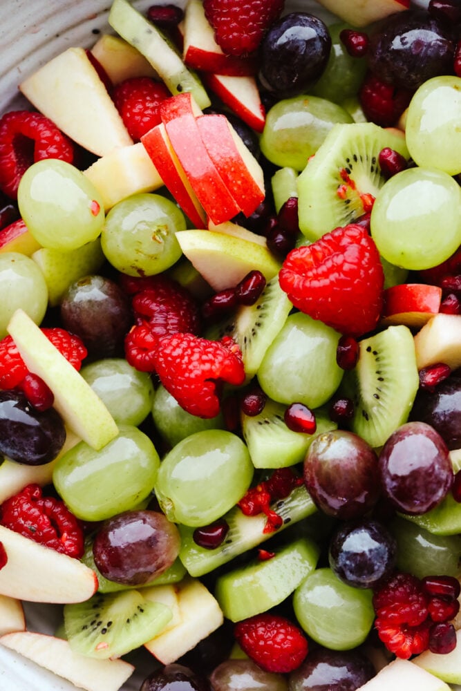 This easy Christmas fruit salad recipe is loaded with red and green fruit making it the perfect light and healthy addition to your holiday table! With a super simple dressing, it comes together quickly and is sure to be a hit! A zoomed in shot of fruit salad.