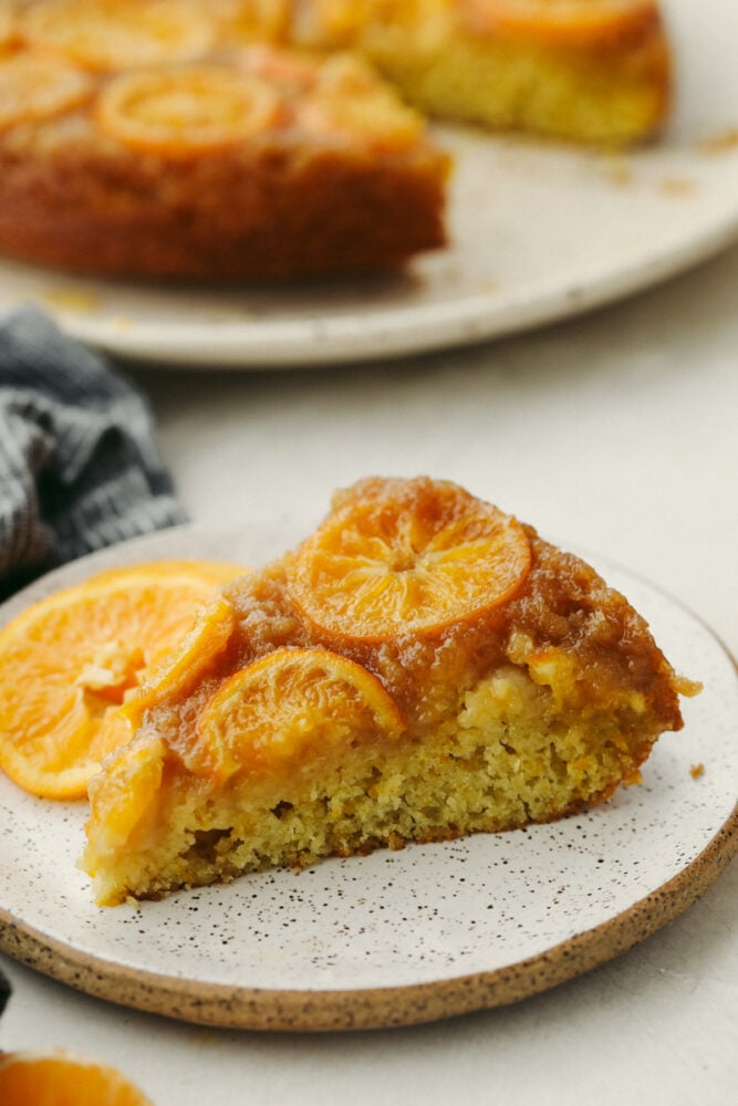 Soft and moist with a sweet juicy flavor, this is one citrus dessert you won't want to miss! Clementine cake is a must-try for the holidays! A slice of clementine cake on a white plate.