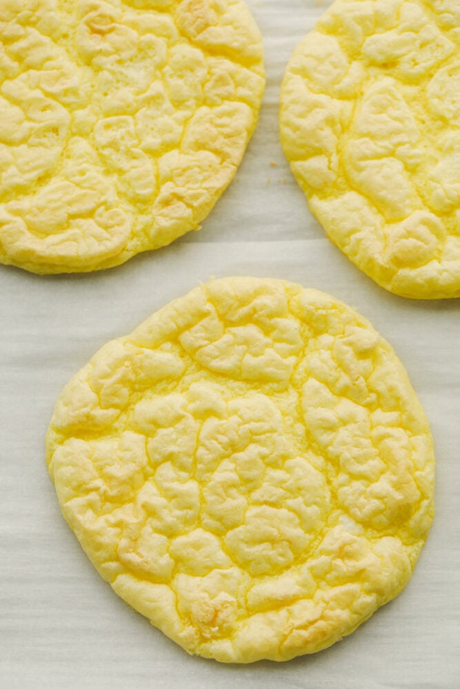 Whipped and airy, this cloud bread really fits its name! It's so delicious and savory that it goes with just about everything. Bake this up and watch it fly off of your table! Baked cloud bread on parchment paper.