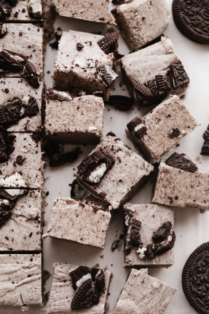 Fudge is a classic holiday treat and these cookies and cream flavor really takes it to the next level. Creamy, Oreo fudge just cannot be beat! Squares of fudge on a pan with oreos on top.