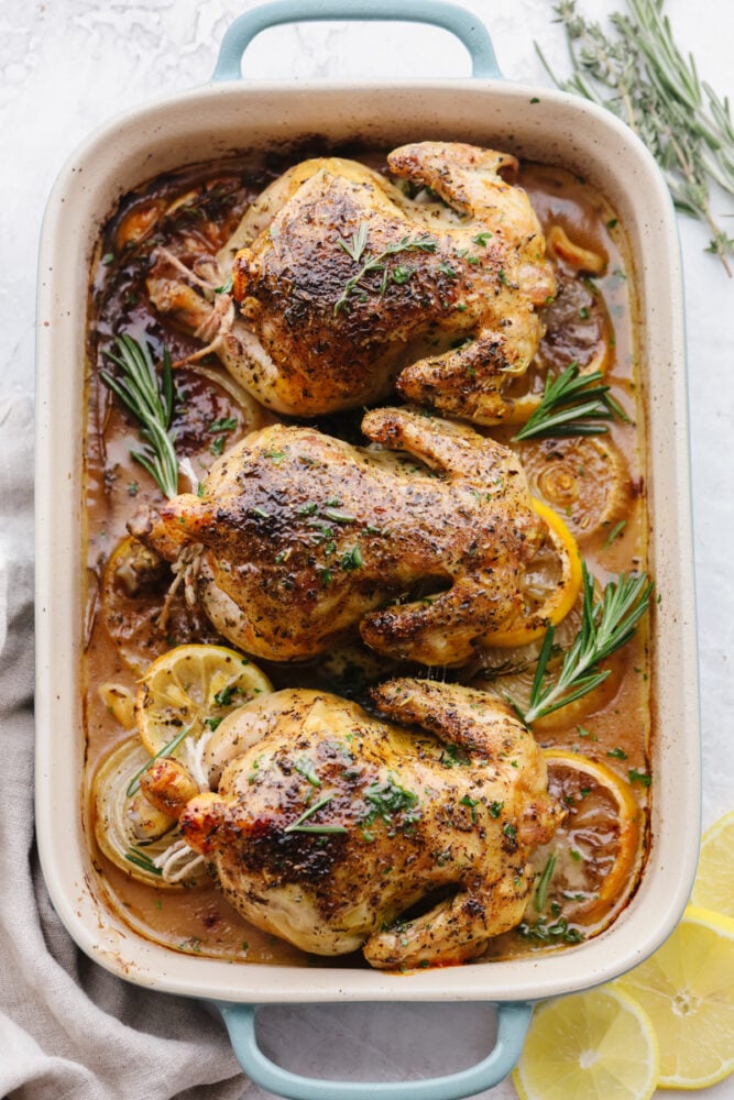 Fancy and baked to crispy perfection these cornish hens will be the star of the show. Not only are they insanely delicious but they are so simple to make! Cooked cornish hens in a baking dish with garnish.