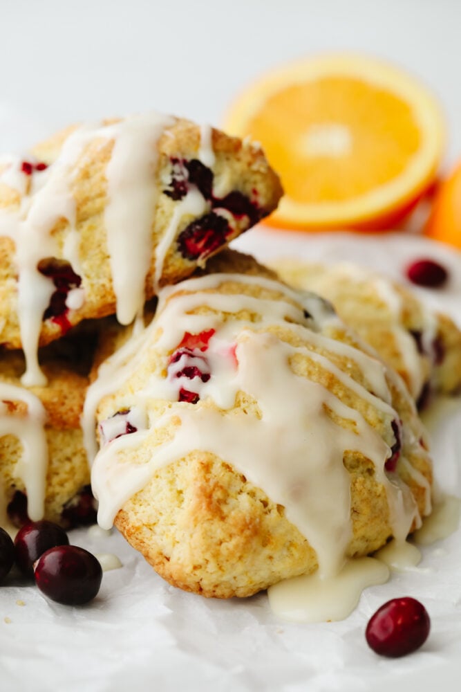 These cranberry orange scones are perfectly soft and fluffy on the inside and crisp and crunchy on the outside. They are bursting with cranberry and orange flavor and make the perfect breakfast! A cranberry orange scone with a glaze on top.