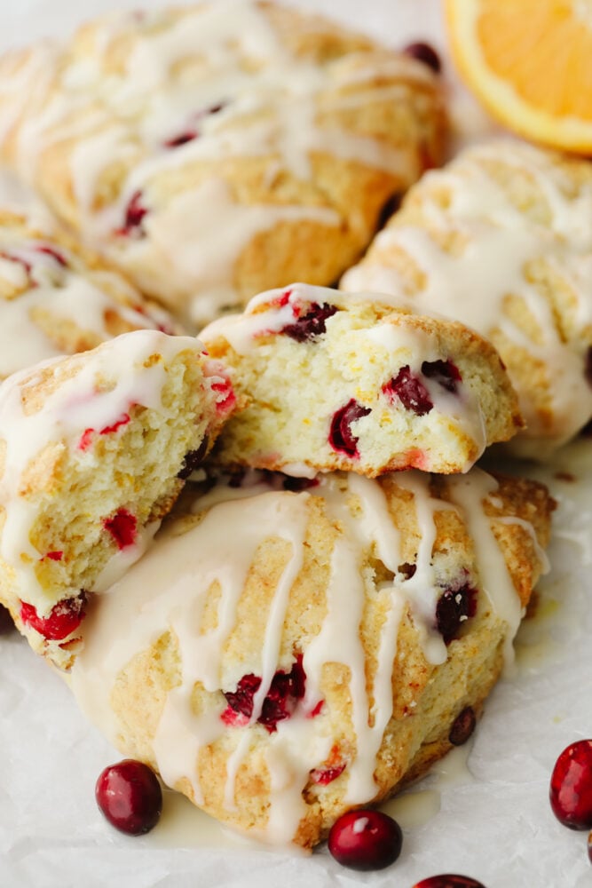 These cranberry orange scones are perfectly soft and fluffy on the inside and crisp and crunchy on the outside. They are bursting with cranberry and orange flavor and make the perfect breakfast! Scones that are stacked and one is broken open so you can see the inside.