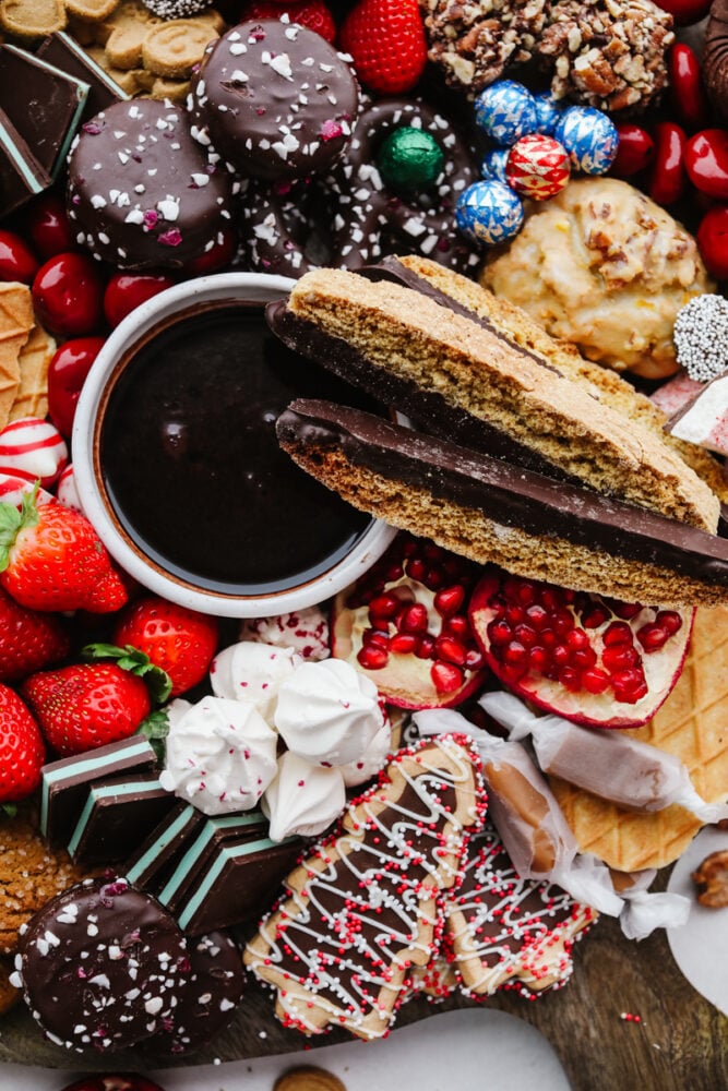 If you are looking for a Christmas dessert to impress your guests then this charcuterie board is it! Stunning and delicious, this board is full of candy, chocolate, cookies, and fruit for the holiday season!ย A zoomed in shot of a Christmas dessert charcuterie board.