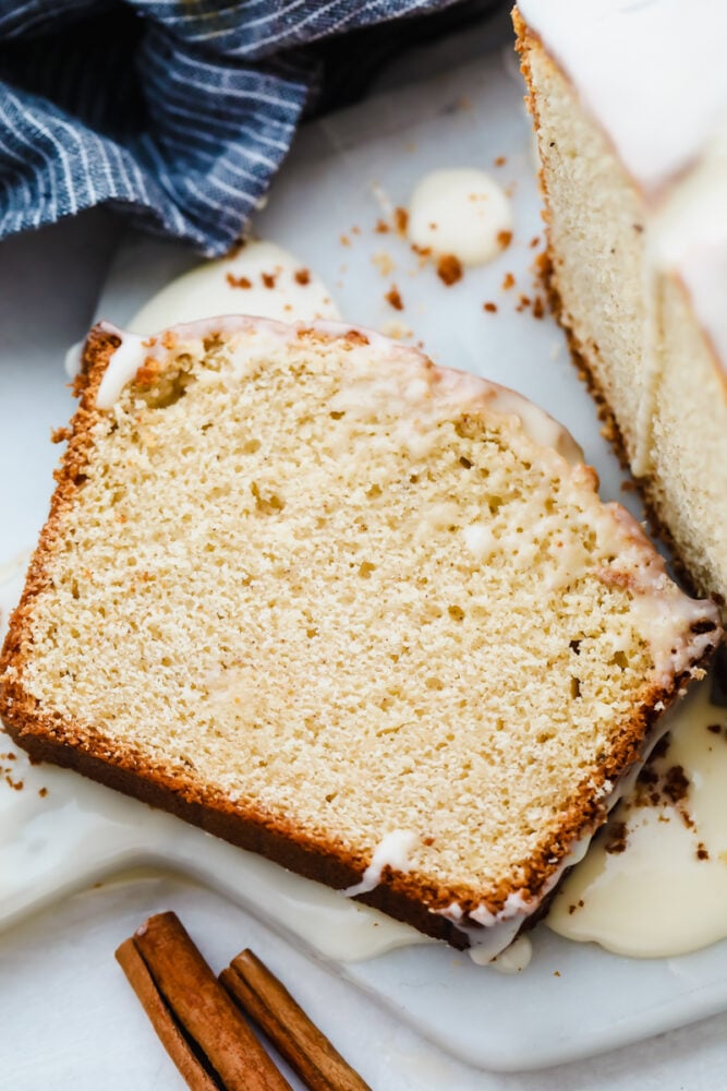 The subtle taste of eggnog in this quick bread is amplified with the ooey-gooey eggnog glaze that is drizzled on top. It's the perfect simple and easy holiday treat! A slice of eggnog quick bread on a plate.