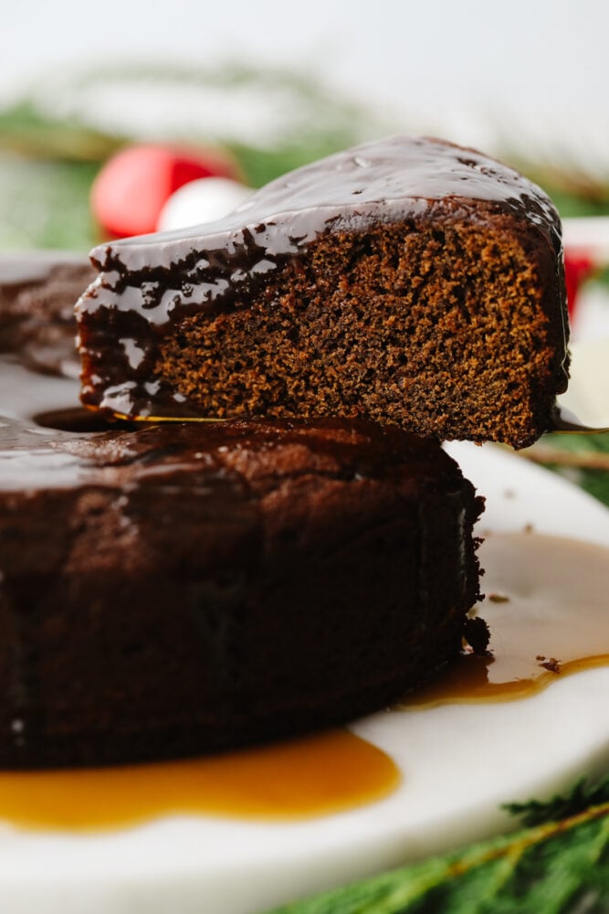 This warm gingerbread cake is made of up delicious and classic holiday flavors. Topped with a homemade caramel sauce, it melts in your mouth and flies off of the table. Your guests will love it! A slice of warm gingerbread cake with caramel sauce.