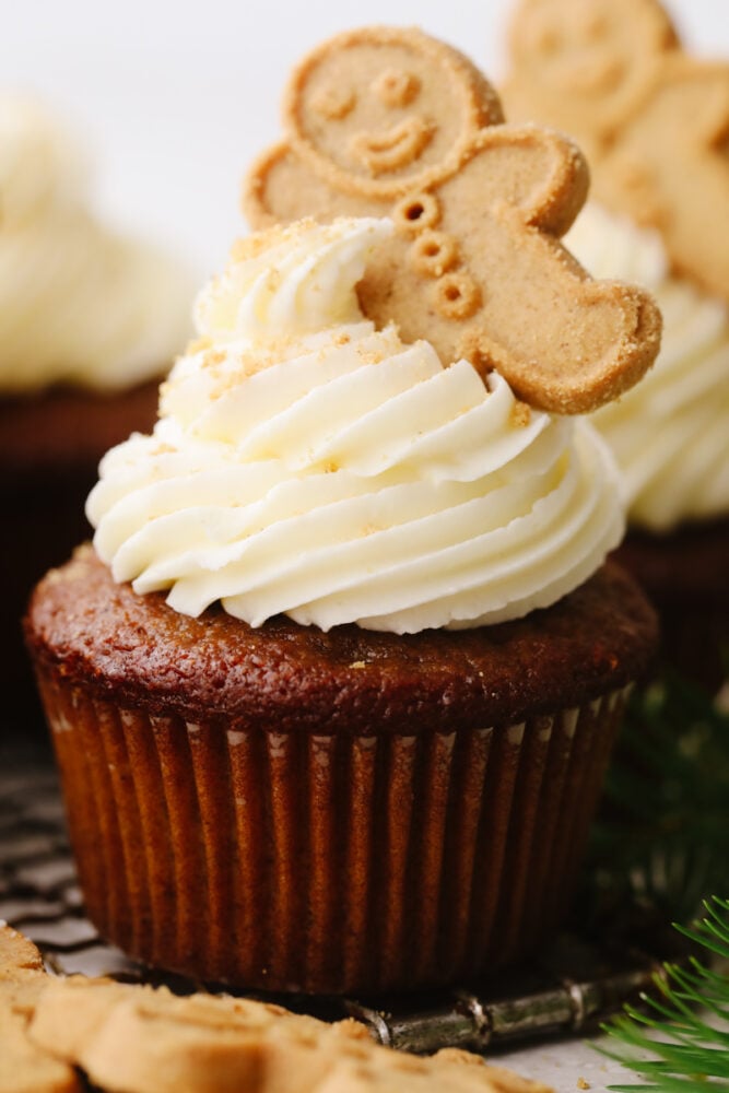 These gingerbread cupcakes are fun, festive, and perfect for the holiday season! It's a moist and tender gingerbread flavored cupcake that is topped with a delicious white chocolate buttercream that everyone will go crazy over. A gingerbread cupcake with white chocolate buttercream frosting on top.