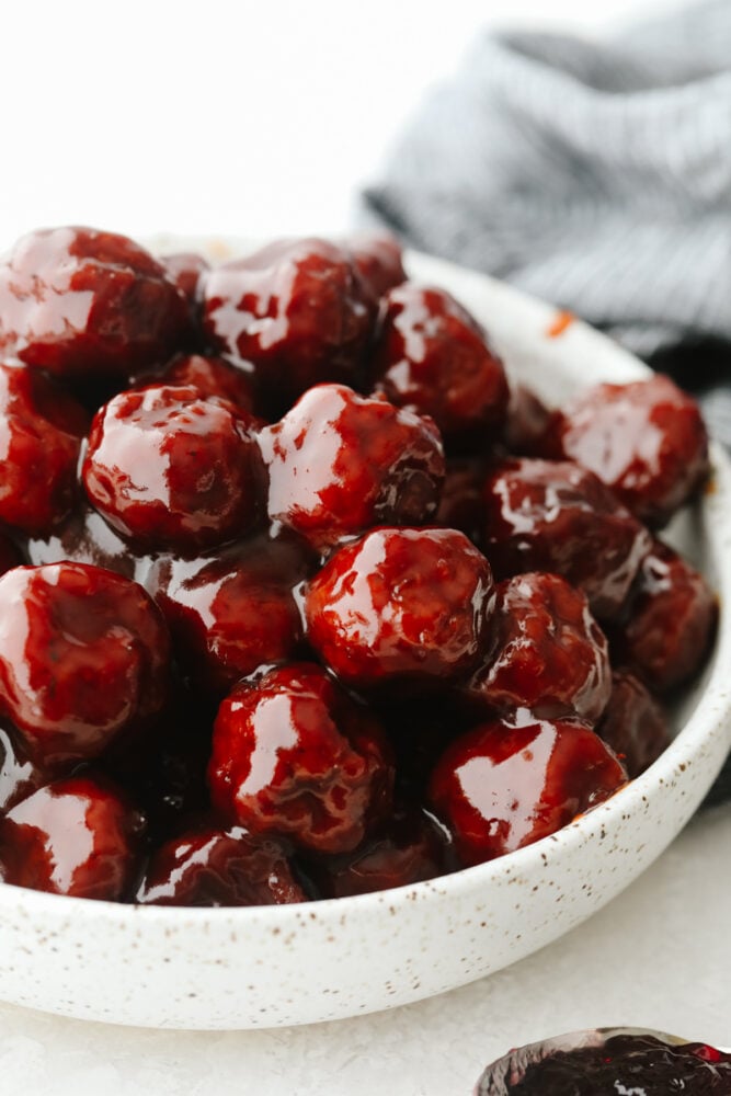 These grape jelly meatballs are so simple and easy and my whole family loves them! They pack so much flavor and are the perfect meal or appetizer for any occasion! A white bowl filled with grape jelly meatballs.