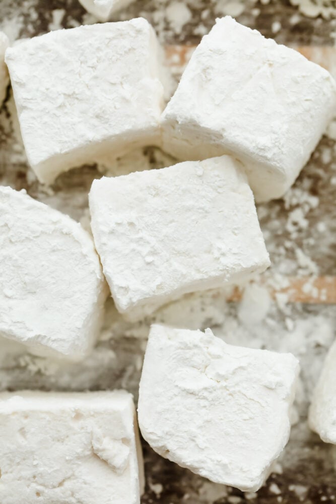 Once you make marshmallows from scratch, you'll never go back! These homemade marshmallows are ultra-soft and delicious, ready for hot chocolate and s'mores! Closeup of homemade marshmallows, dusted in powdered sugar.