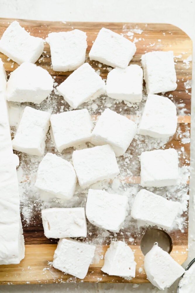Once you make marshmallows from scratch, you'll never go back! These homemade marshmallows are ultra-soft and delicious, ready for hot chocolate and s'mores! Homemade marshmallows on a wooden cutting board.