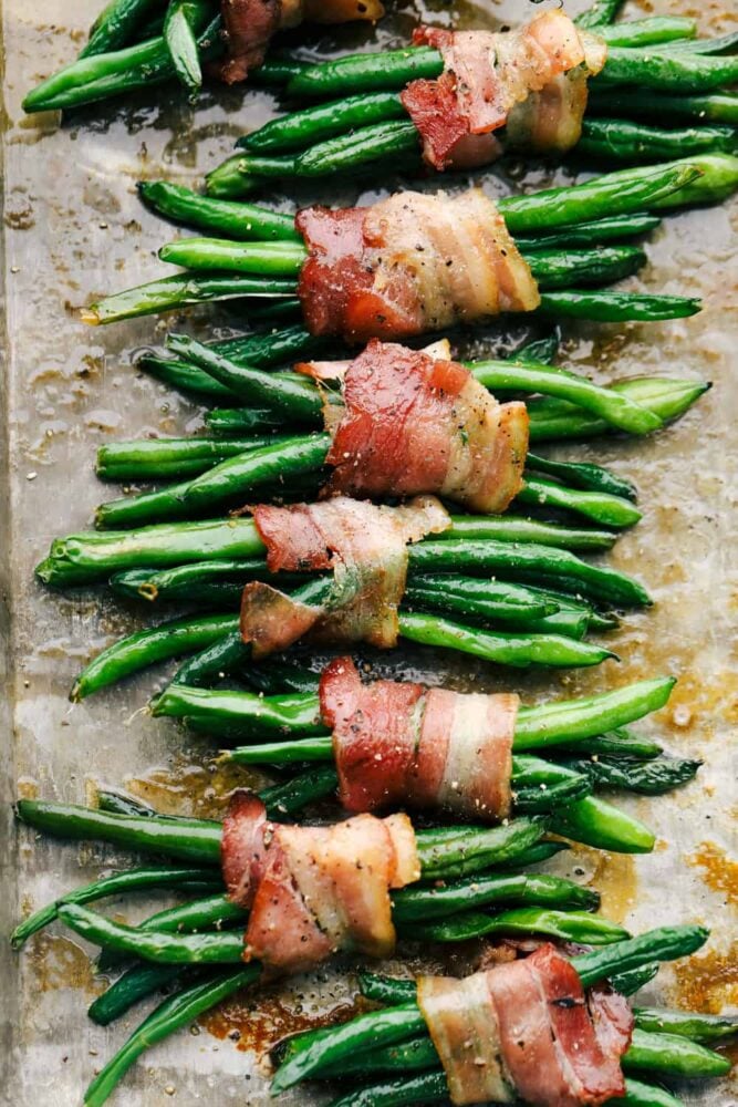 These green bean bundles are the ultimate side dish! Crispy bacon wrapped around succulent green beans will be your new tradition this holiday season! Beans wrapped in bacon, cooked and ready to eat.