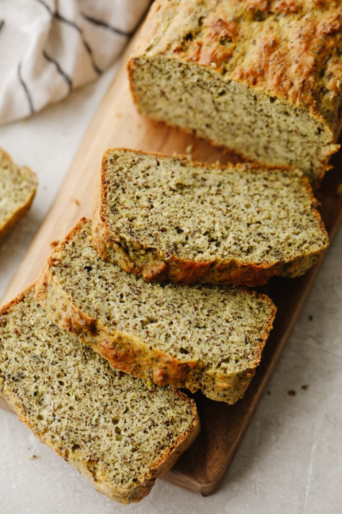 This keto bread is simple and full of delicious flavor! The ingredients are super healthy but that doesn't take away from its amazingly moist texture and taste! A loaf of keto bread that is sliced on a cutting board.