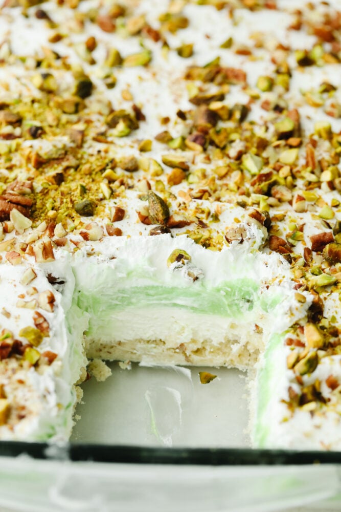 This layered pistachio dessert is insanely delicious! It has the perfect crust that is then topped with layers of creamy cheesecake and pistachio pudding! A view of all of the layers of a pistachio dessert.
