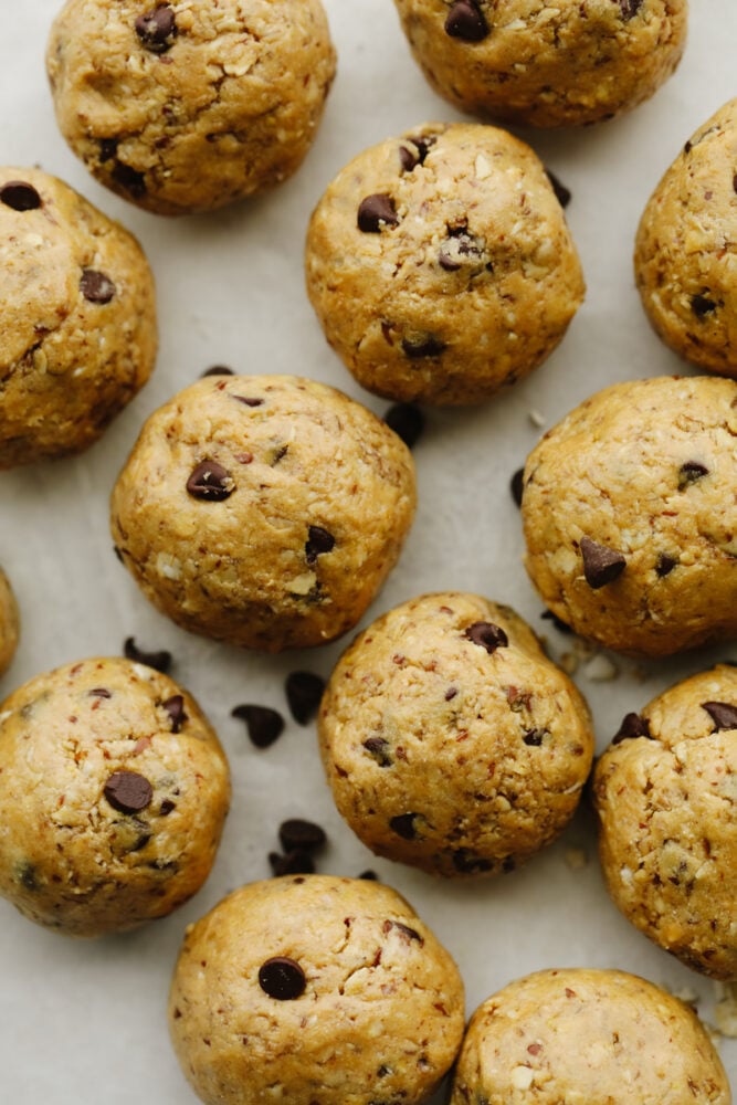 Protein balls are a delicious no-bake treat! Start your new year right by snacking on these tasty, healthy bites loaded with chocolate chips and peanut butter! Closeup of protein balls on parchment paper.